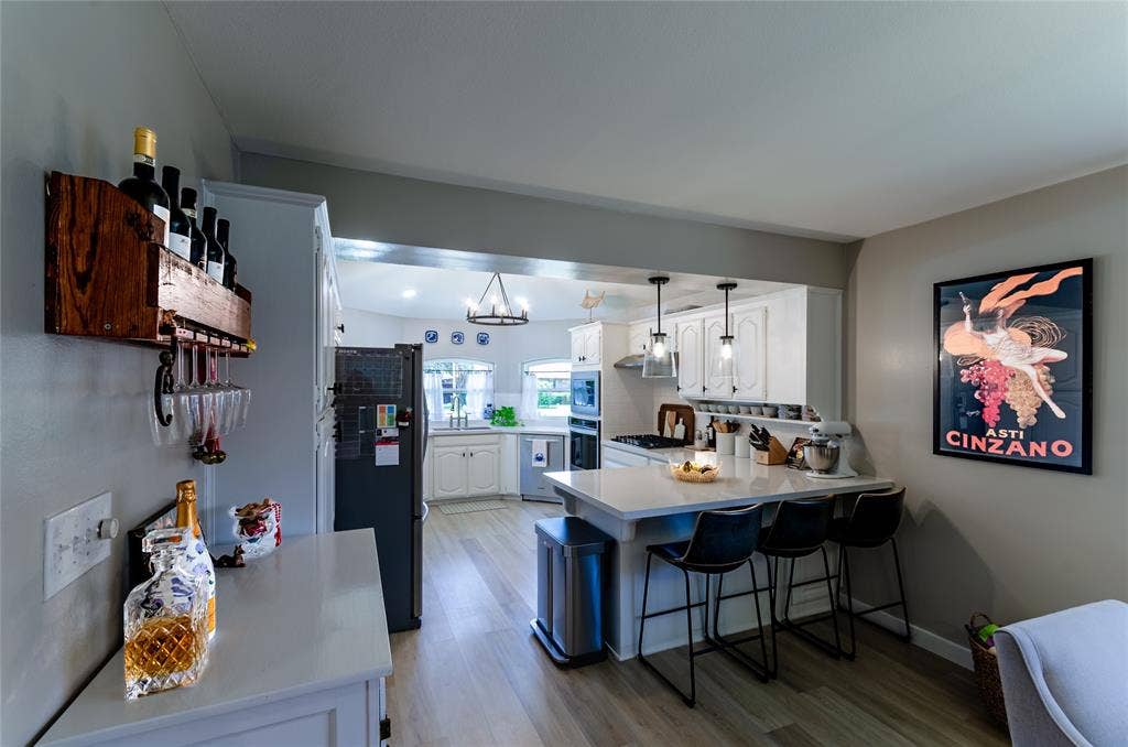 Kitchen featuring white cabinetry, a central island with countertop seating, stainless steel appliances, and pendant lighting