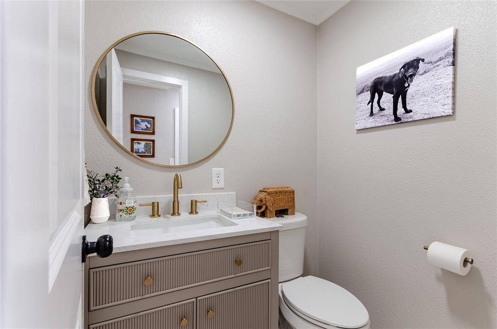 Vanity with fluted paneling and brass-finish hardware, rectangular undermount sink, white countertop, and brass-finish faucet