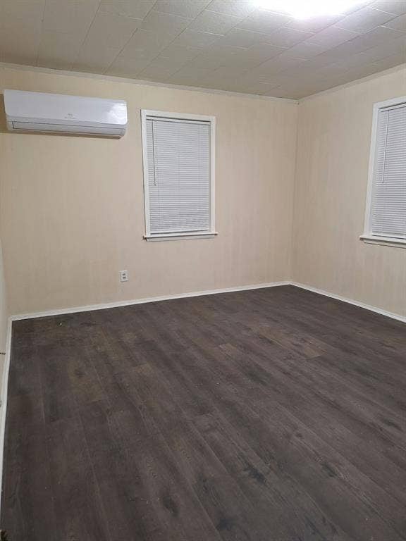 Neutral interior space featuring wood-finish flooring, two windows with integrated blinds, and a wall-mounted ductless mini-split HVAC unit