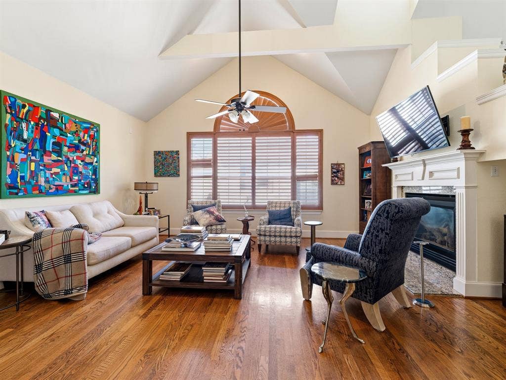 14567 Juliard Lane, Addison, TX 75001 Vaulted ceiling, wood-finish flooring, fireplace with custom mantel, arched window, and ceiling fan