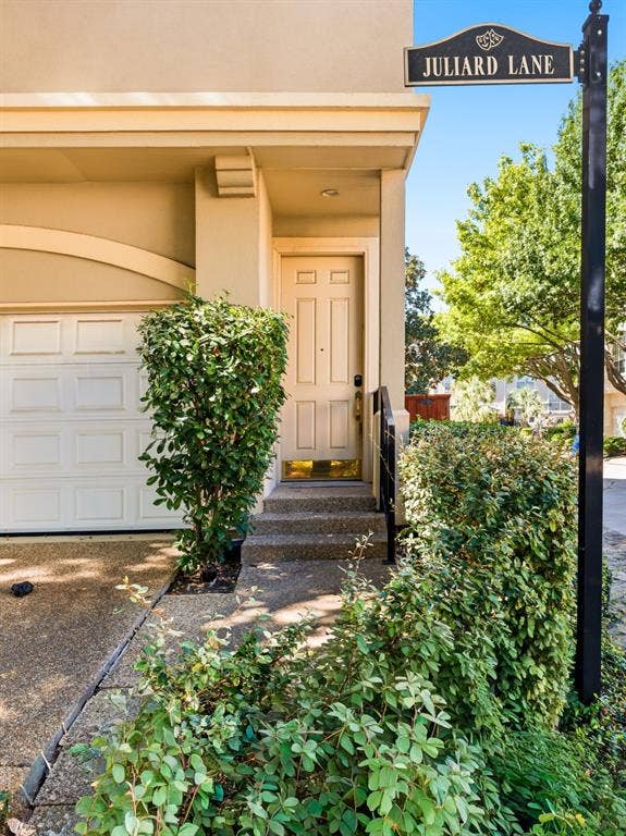 14567 Juliard Lane, Addison, TX 75001 Exterior entrance featuring a six-panel front door, concrete steps, and a multi-section garage door with an arched header