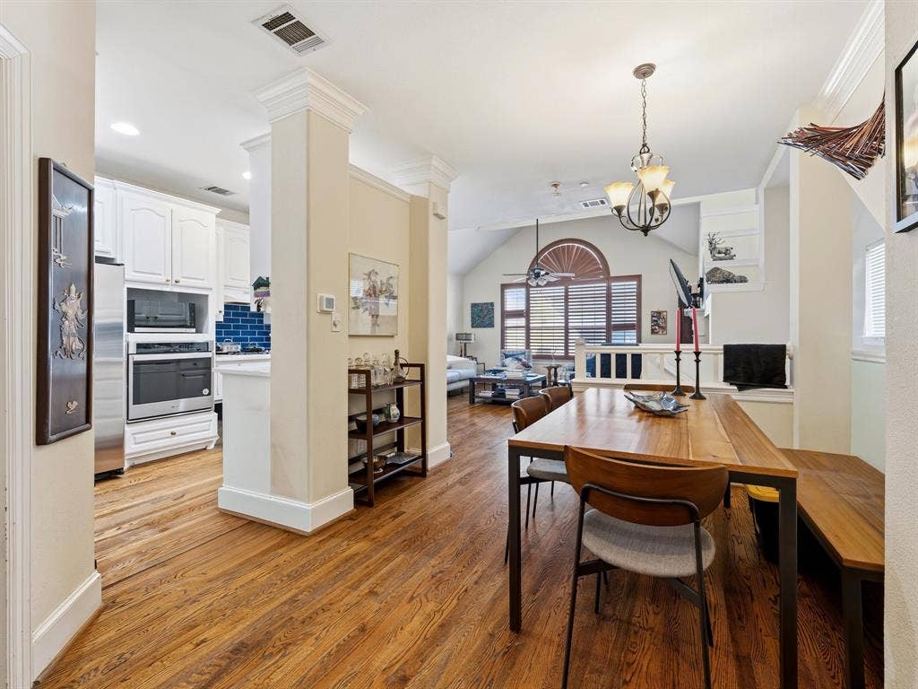 14567 Juliard Lane, Addison, TX 75001 Wood-finish flooring, white cabinetry, built-in stainless steel double oven, arched window with decorative molding, and crown molding