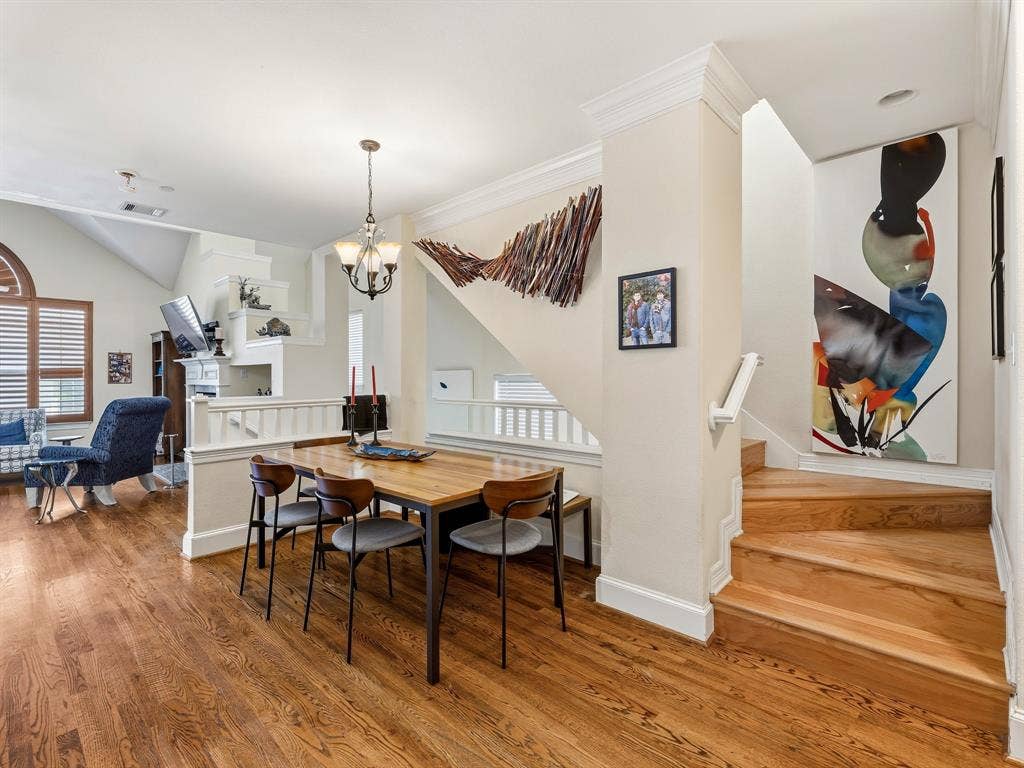 14567 Juliard Lane, Addison, TX 75001 Hardwood flooring, crown molding, open-tread wood staircase with a white handrail, and a tiered architectural fireplace feature