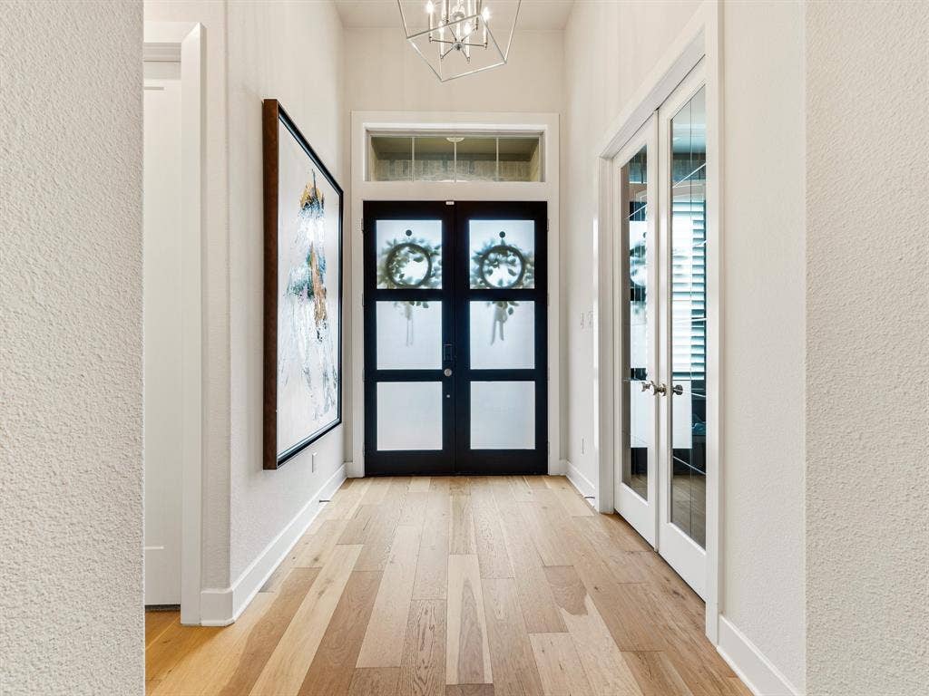Foyer featuring wood-finish flooring, double entry doors with frosted glass panels, a transom window, geometric pendant lighting, and French doors