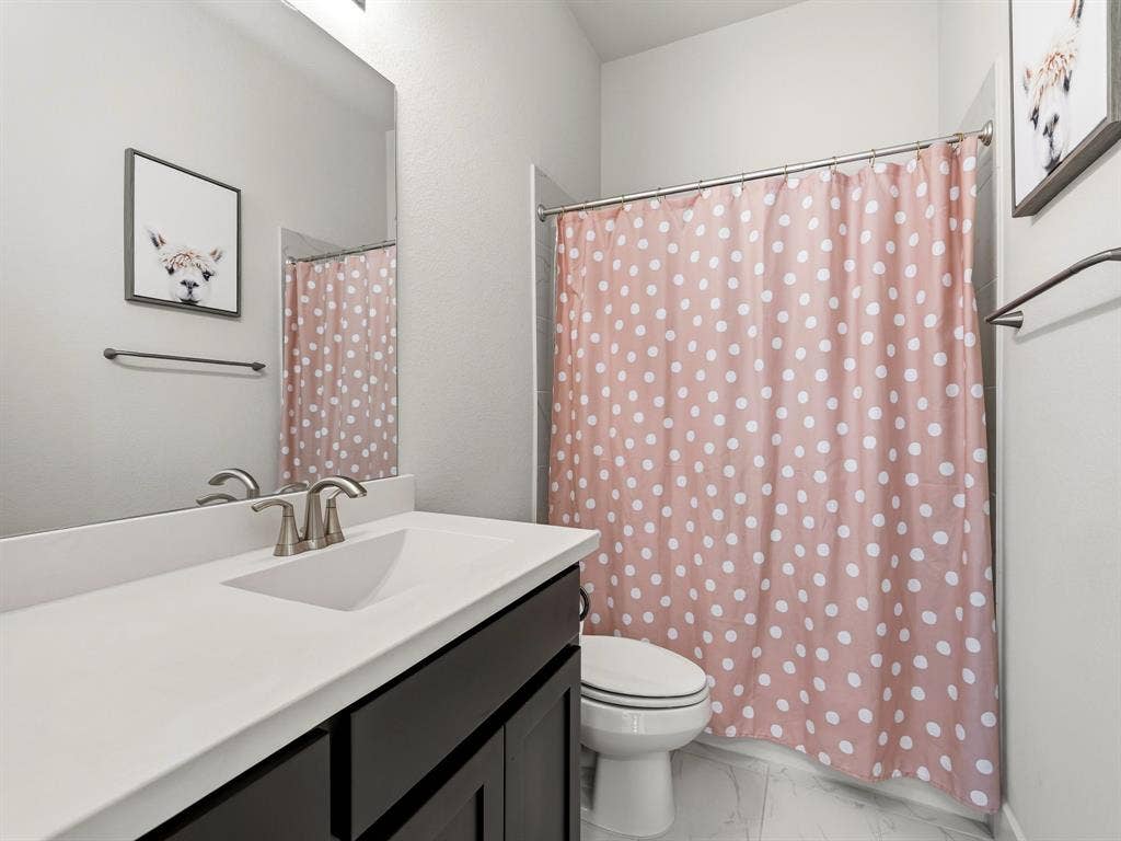 Dark-finish vanity featuring an integrated basin, brushed nickel faucet, large wall-mounted mirror, and tile flooring