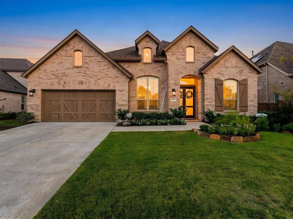 Brick exterior featuring multiple gables, arched window details, wooden shutters, and a multi-car garage with carriage-style doors