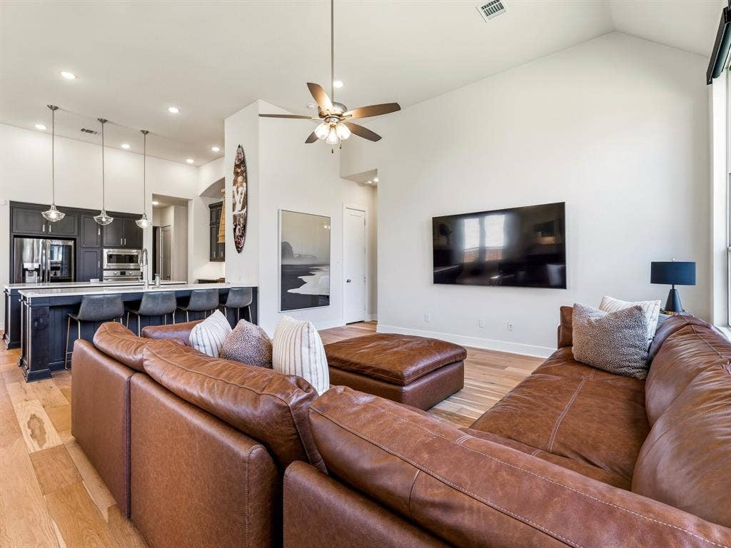 Vaulted ceilings, wood-finish flooring, recessed lighting, kitchen island with pendant lighting, and dark-toned cabinetry