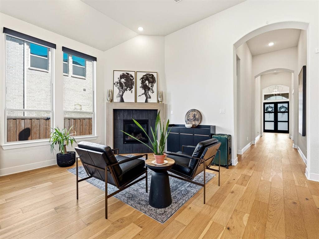 Vaulted ceilings, wood-finish flooring, fireplace with a stone-surround mantel, and arched entryways