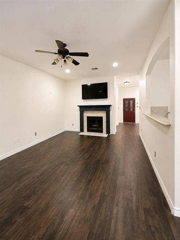 1207 Fox Trail Drive, Allen, TX 75002 Living area featuring wood-finish flooring, a fireplace with a mantel and tile surround, a multi-blade ceiling fan, and a pass-through opening with a ledge