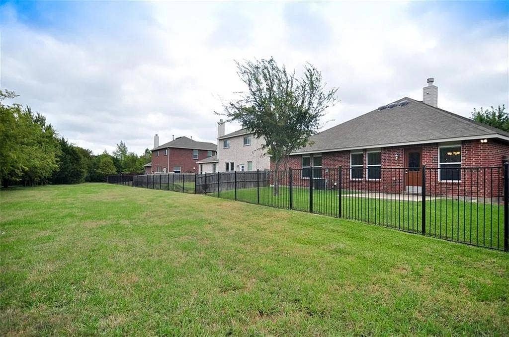 1207 Fox Trail Drive, Allen, TX 75002 Spacious backyard featuring a brick exterior, shingle roof, and a black metal perimeter fence