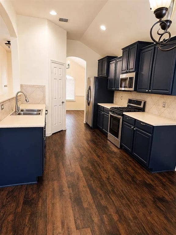 1207 Fox Trail Drive, Allen, TX 75002 Kitchen featuring dark-toned cabinetry, light-colored countertops, stainless steel appliances, tile backsplash, and wood-finish flooring
