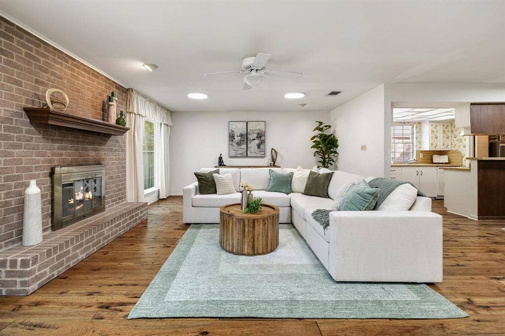 3209 Sheffield Street, Irving, TX 75062 Living area featuring wood-finish flooring, a floor-to-ceiling brick fireplace with a wood mantel, and integrated ceiling lights