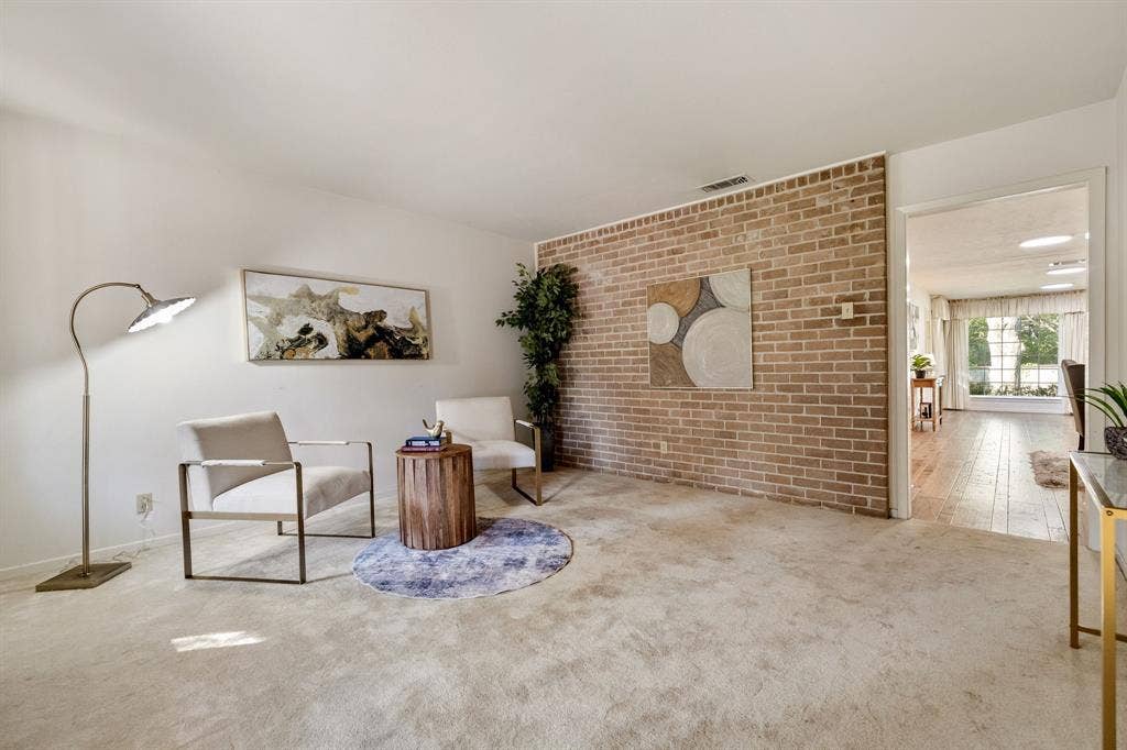 3209 Sheffield Street, Irving, TX 75062 Living area featuring a floor-to-ceiling brick accent wall and neutral carpeting