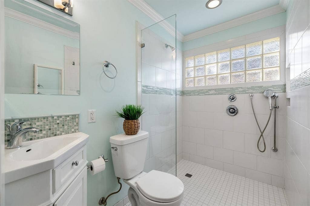 3209 Sheffield Street, Irving, TX 75062 Bathroom featuring a vanity with integrated sink, glass-enclosed shower with tile surround, mosaic accent tiling, and glass block window
