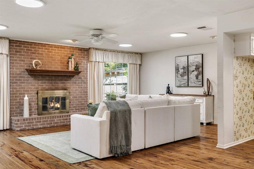 3209 Sheffield Street, Irving, TX 75062 Living space featuring wood-finish flooring, a floor-to-ceiling brick fireplace with a wood mantel, a brass-finish fireplace enclosure, and recessed lighting