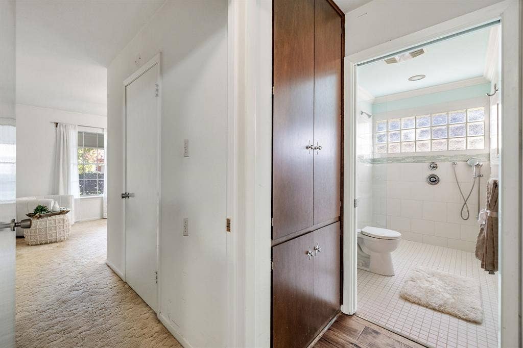 3209 Sheffield Street, Irving, TX 75062 Built-in floor-to-ceiling wood cabinetry, bathroom featuring a glass block window, wall-mounted shower fixture with handheld sprayer, white tile flooring, and neutral wall tones