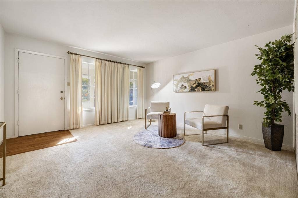 3209 Sheffield Street, Irving, TX 75062 Neutral-toned interior space featuring light carpeting, wood-finish flooring at the entryway, and large windows with integrated window treatments
