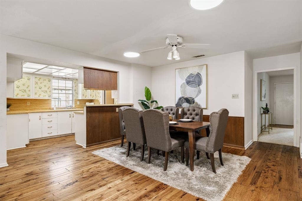 3209 Sheffield Street, Irving, TX 75062 Dining area featuring wood-finish flooring, wainscoting, a ceiling fan with integrated lighting, and a kitchen pass-through with built-in cabinetry