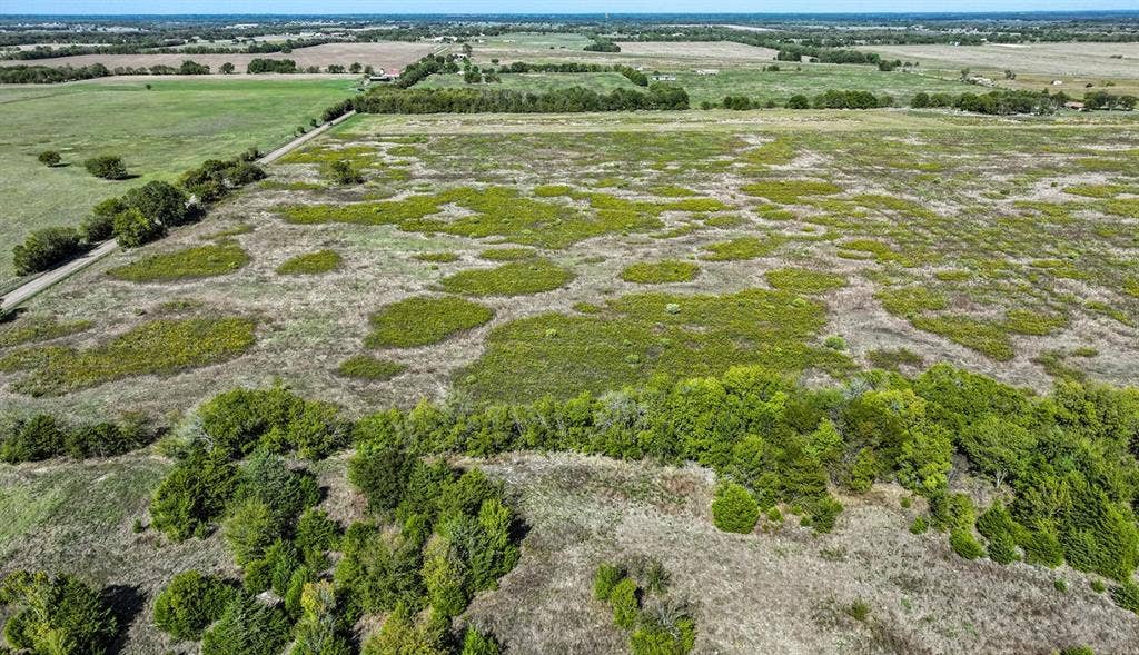 0 County Road 4604, Commerce, TX 75428 Expansive acreage featuring cleared pasture, clusters of mature trees, and unpaved perimeter access