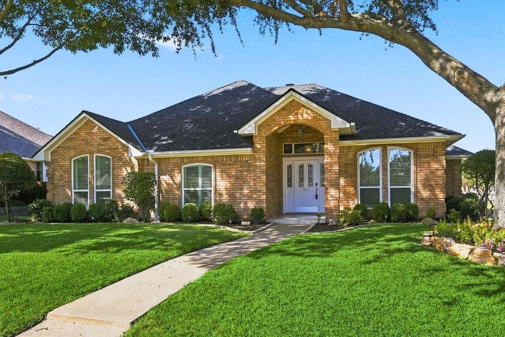 210 Santa Fe Trail, Waxahachie, TX 75165 Brick exterior with a covered arched entryway, high-pitched roofline, decorative glass-paneled front door, and manicured front lawn