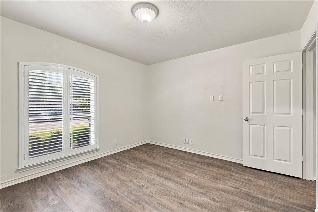 210 Santa Fe Trail, Waxahachie, TX 75165 Room featuring wood-finish flooring, arched window with plantation shutters, six-panel interior door, and flush-mount ceiling light fixture