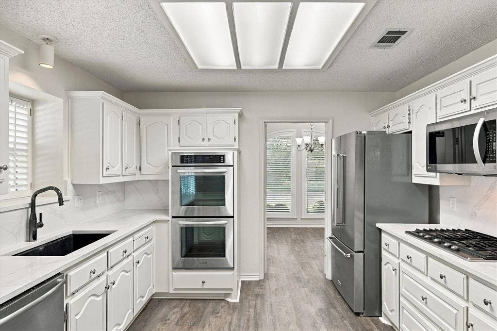 210 Santa Fe Trail, Waxahachie, TX 75165 Kitchen featuring white cabinetry, quartz countertops, stainless steel double wall ovens, a stainless steel gas cooktop, and a matte black faucet with an undermount sink
