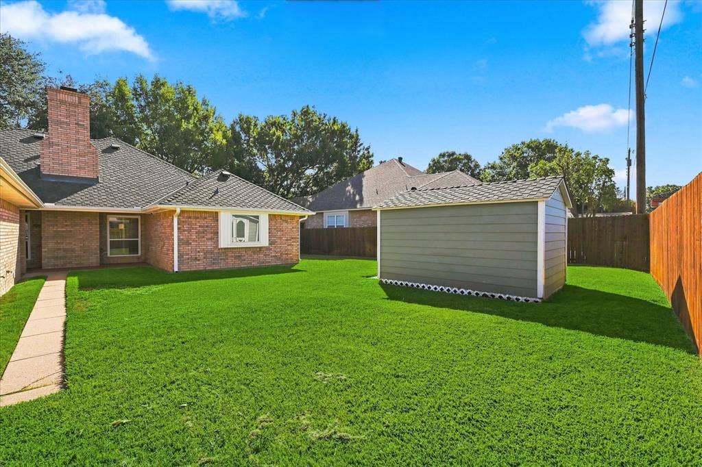 210 Santa Fe Trail, Waxahachie, TX 75165 Backyard featuring a brick-exterior house, detached storage structure, concrete walkway, and wood perimeter fencing