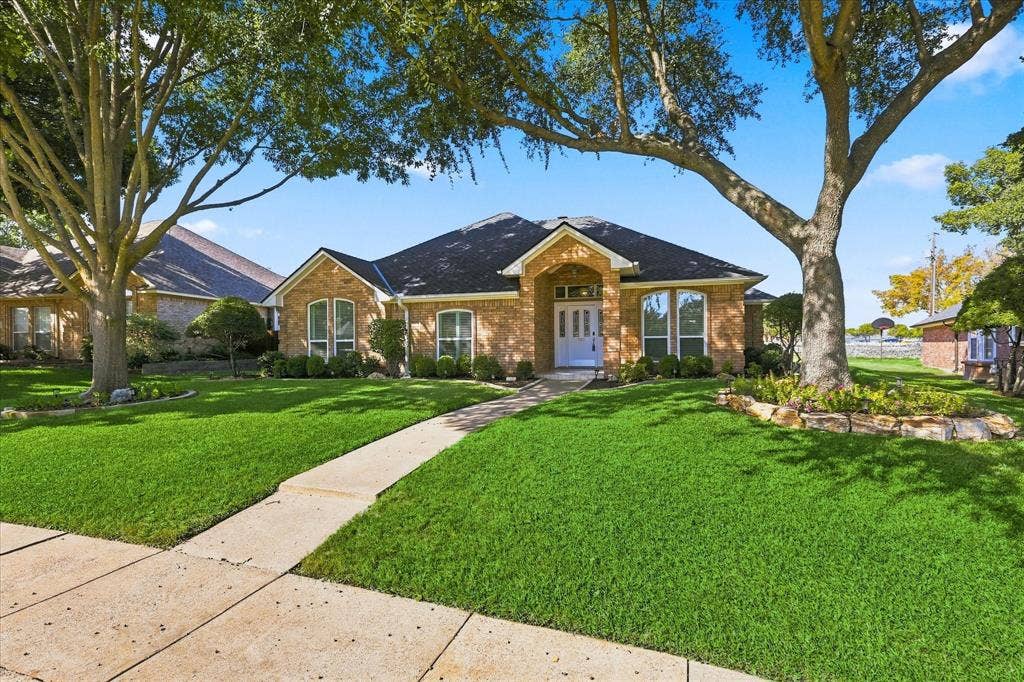 210 Santa Fe Trail, Waxahachie, TX 75165 Single-story brick exterior featuring a multi-gabled roofline, arched windows, covered entryway, and mature landscape trees