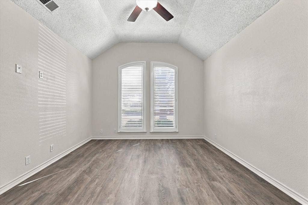 210 Santa Fe Trail, Waxahachie, TX 75165 Vaulted ceilings, wood-finish flooring, two arched windows with horizontal blinds, and a central ceiling fan with integrated light fixture