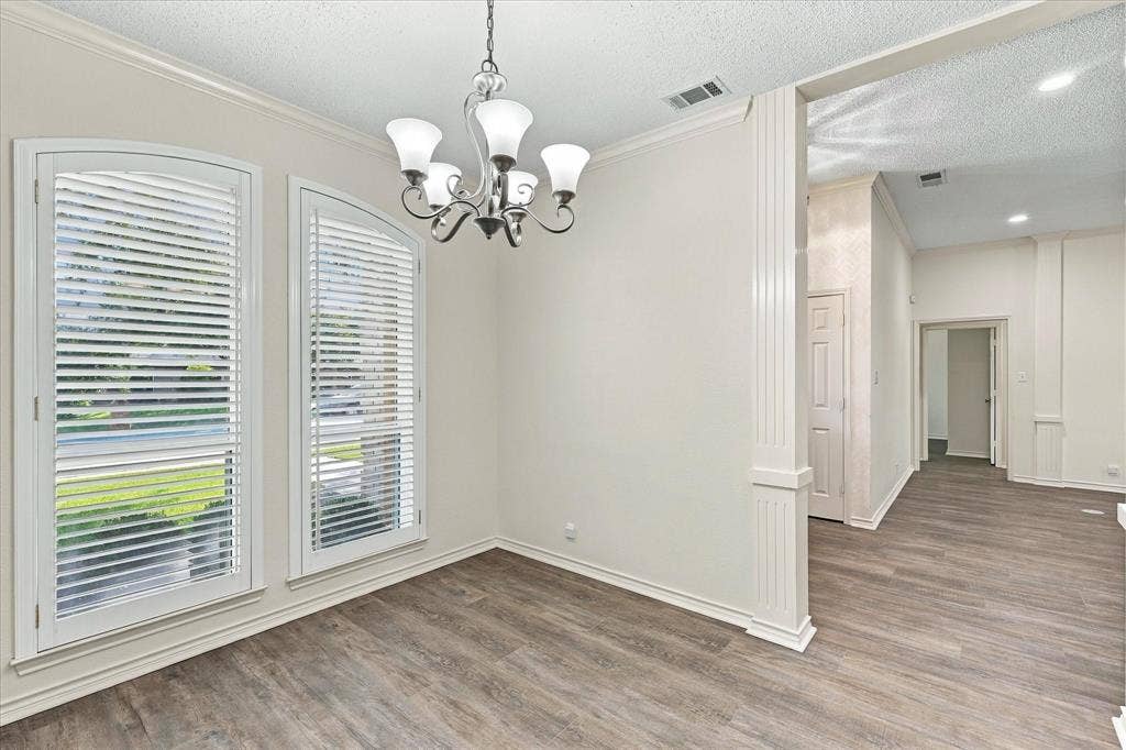 210 Santa Fe Trail, Waxahachie, TX 75165 Arched windows with shutters, wood-finish flooring, and a multi-light chandelier featuring a fluted architectural column