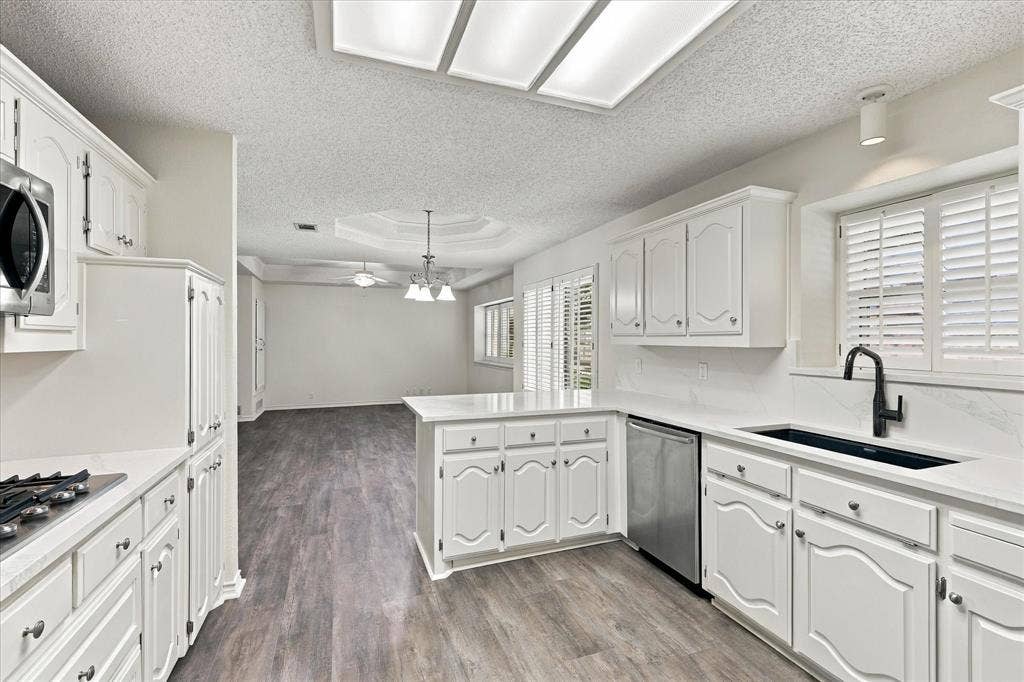 210 Santa Fe Trail, Waxahachie, TX 75165 Kitchen featuring white cabinetry, wood-finish flooring, stone-style countertops, stainless steel appliances, and a matte black gooseneck faucet