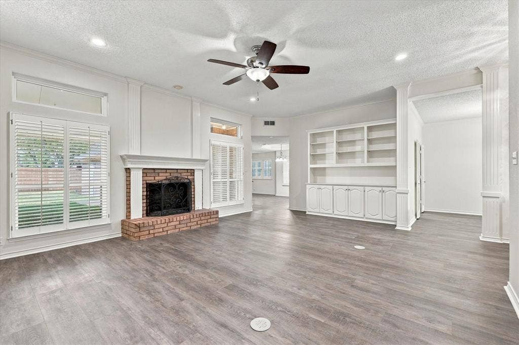 210 Santa Fe Trail, Waxahachie, TX 75165 Brick fireplace with decorative mantel, wood-finish flooring, built-in cabinetry, dual window sets with plantation shutters, and recessed lighting