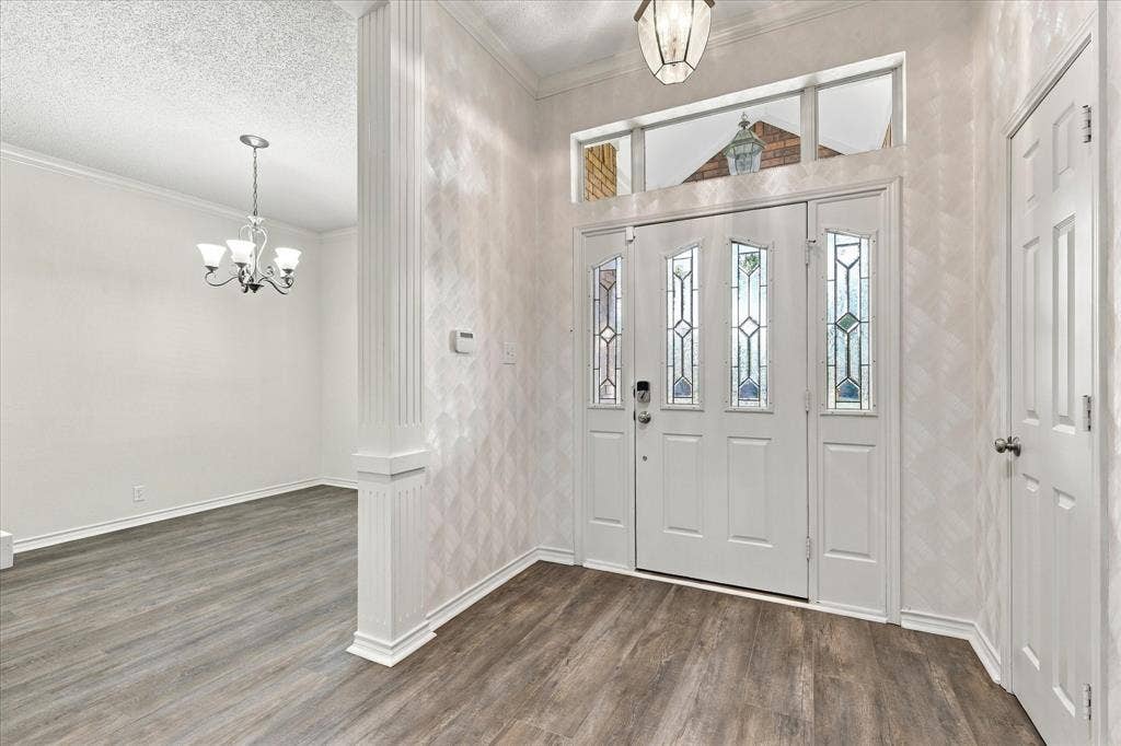 210 Santa Fe Trail, Waxahachie, TX 75165 Entryway featuring a front door with decorative glass panels, a transom window, wood-finish flooring, a fluted column, and a multi-arm chandelier