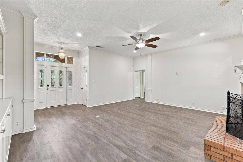 210 Santa Fe Trail, Waxahachie, TX 75165 Living area featuring wood-finish flooring, a brick fireplace, a multi-pane front door with glass inserts, architectural columns, and a ceiling fan with integrated lighting