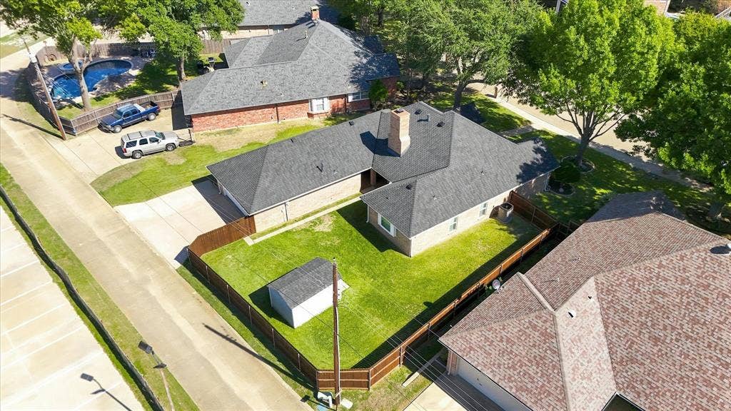 210 Santa Fe Trail, Waxahachie, TX 75165 Aerial view of a corner lot property featuring a brick exterior, a shingle roof with a masonry chimney, a fenced-in backyard, and a paved driveway