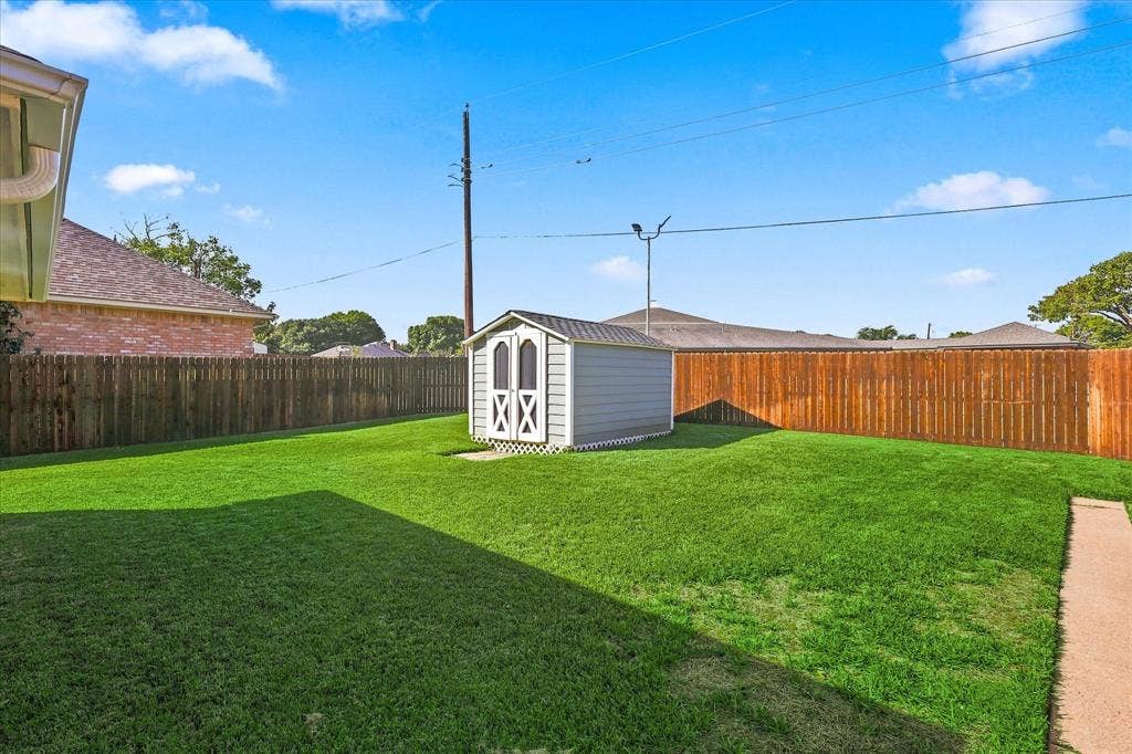 210 Santa Fe Trail, Waxahachie, TX 75165 Fenced backyard featuring a manicured lawn, a detached storage shed, and a concrete pathway