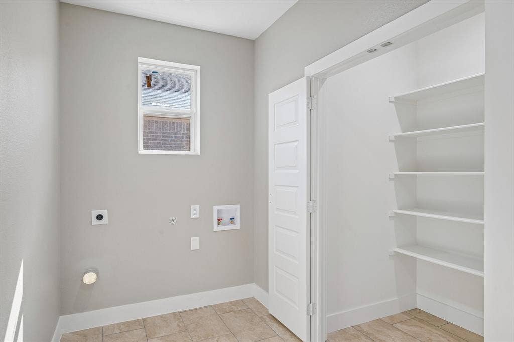 1221 S Rockwall Avenue, Terrell, TX 75160 Utility room featuring neutral wall paint, tile flooring, a window, and built-in white shelving