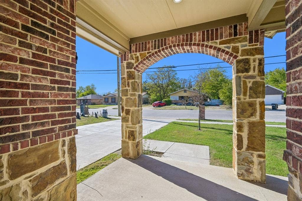 1221 S Rockwall Avenue, Terrell, TX 75160 Covered porch featuring stone-clad pillars, arched masonry detailing, and a concrete foundation