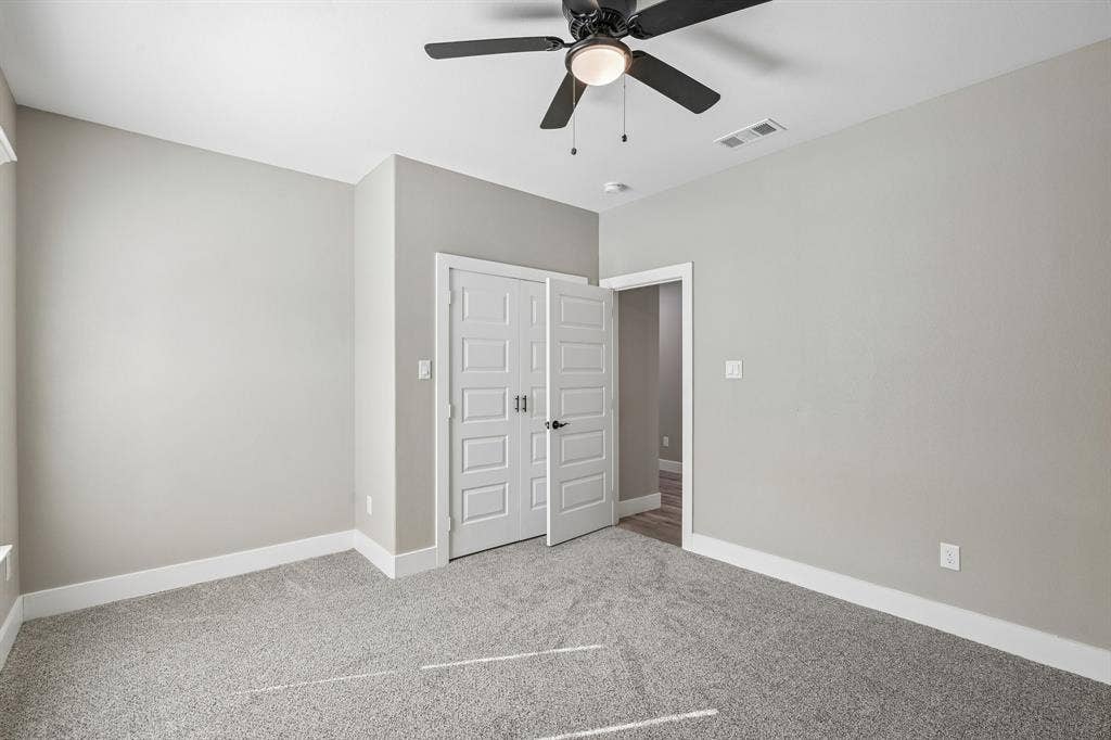 1221 S Rockwall Avenue, Terrell, TX 75160 Neutral-toned interior featuring wall-to-wall carpeting, a multi-panel door closet, and a ceiling fan with integrated lighting