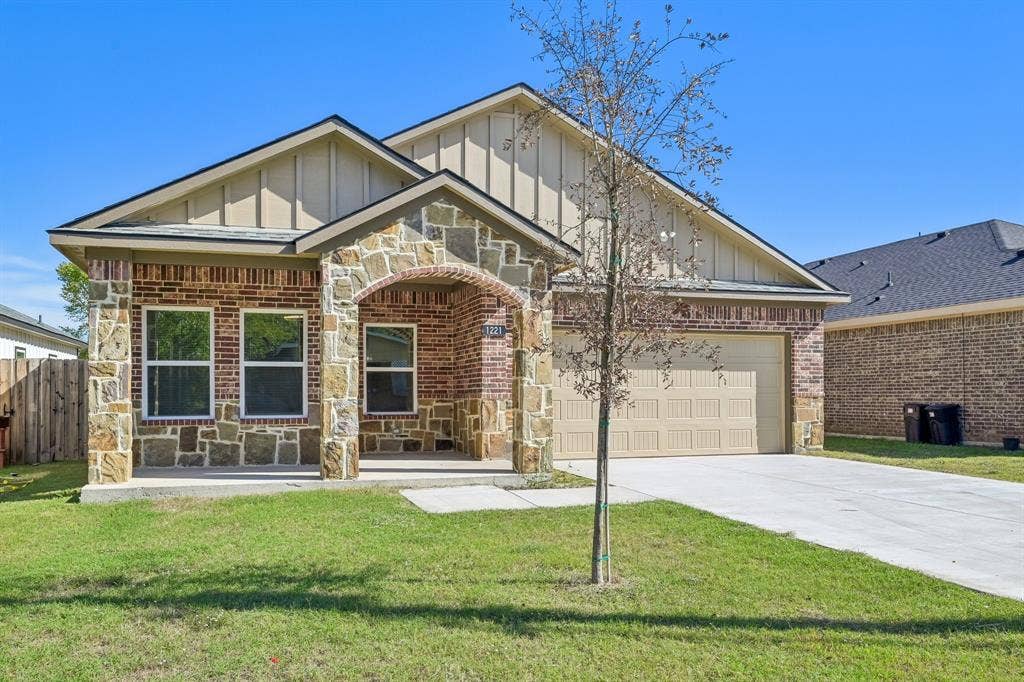 1221 S Rockwall Avenue, Terrell, TX 75160 Exterior facade featuring a combination of brick and stone masonry, vertical siding, an arched covered entryway, and an attached two-car garage