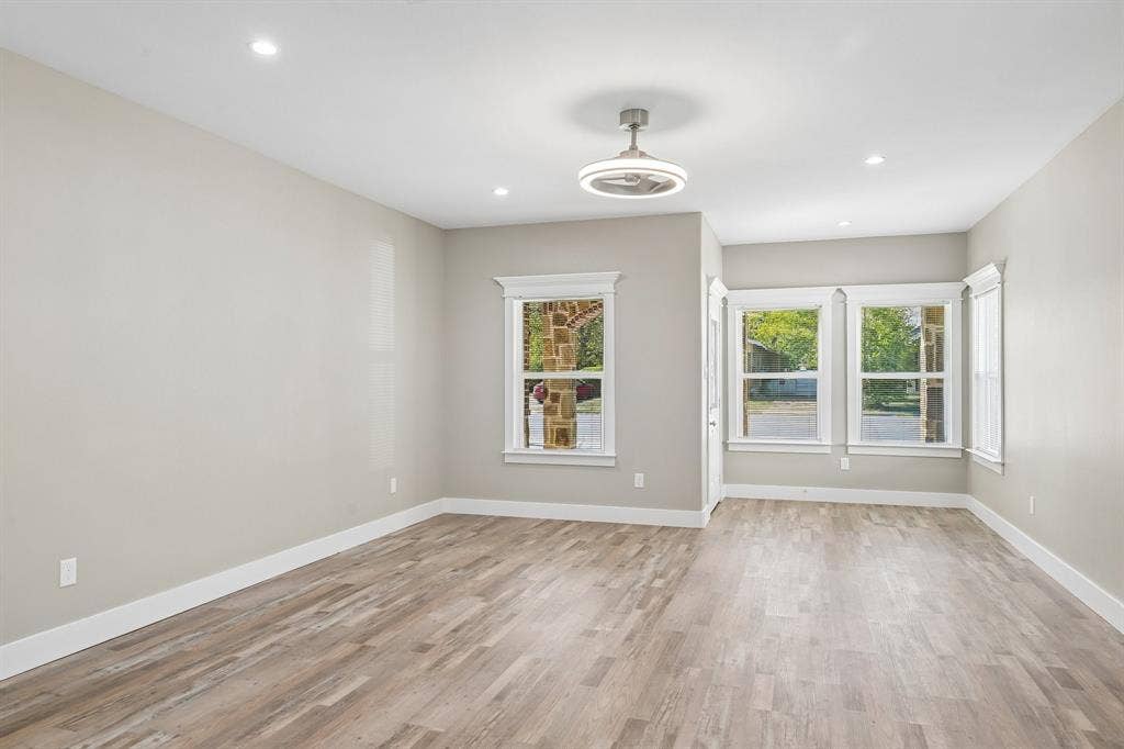 1221 S Rockwall Avenue, Terrell, TX 75160 Neutral interior space featuring wood-finish flooring, recessed lighting, a modern ceiling fan, and multiple windows with stone exterior detailing