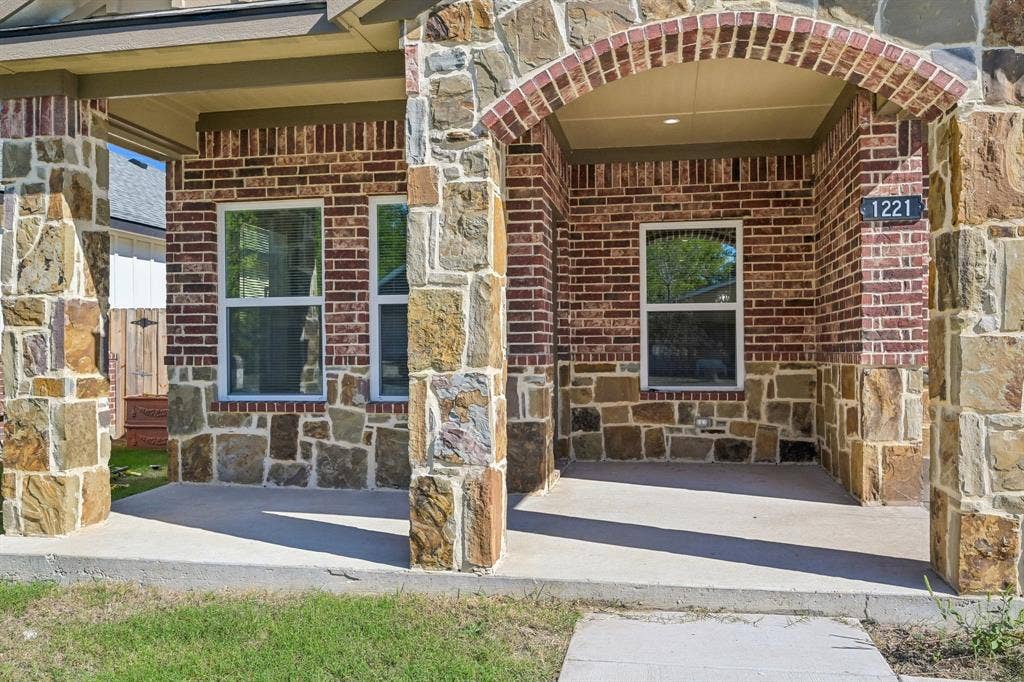 1221 S Rockwall Avenue, Terrell, TX 75160 Exterior facade featuring multi-textured stone masonry, red brick accents, an arched covered porch, and columns with stone veneer