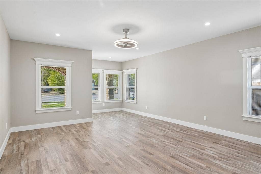 1221 S Rockwall Avenue, Terrell, TX 75160 Neutral-toned interior featuring wood-finish flooring, recessed lighting, crown-molding window trim, and a modern circular ceiling fan