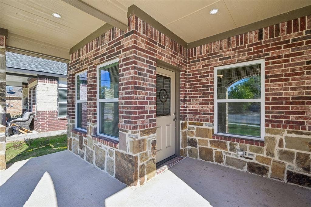 1221 S Rockwall Avenue, Terrell, TX 75160 Covered entryway featuring a multi-textured exterior of mixed brick and stone masonry, recessed ceiling lighting, and a single-light panel front door