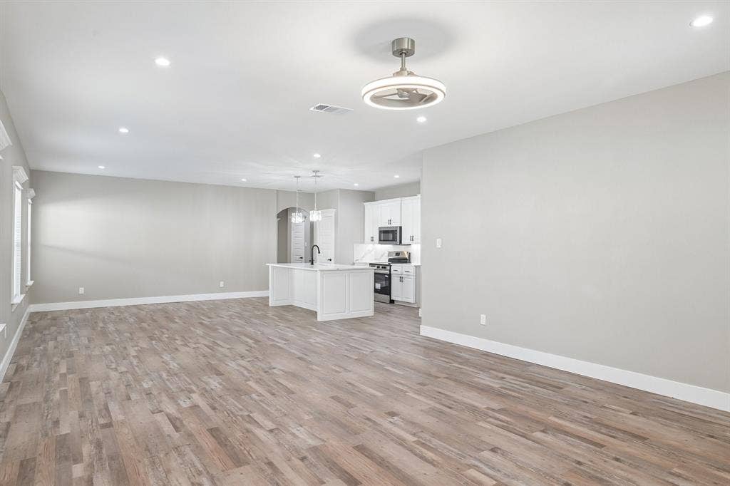 1221 S Rockwall Avenue, Terrell, TX 75160 Open-concept interior featuring wood-finish flooring, recessed lighting, a modern ceiling fan, and a kitchen equipped with a central island and white cabinetry