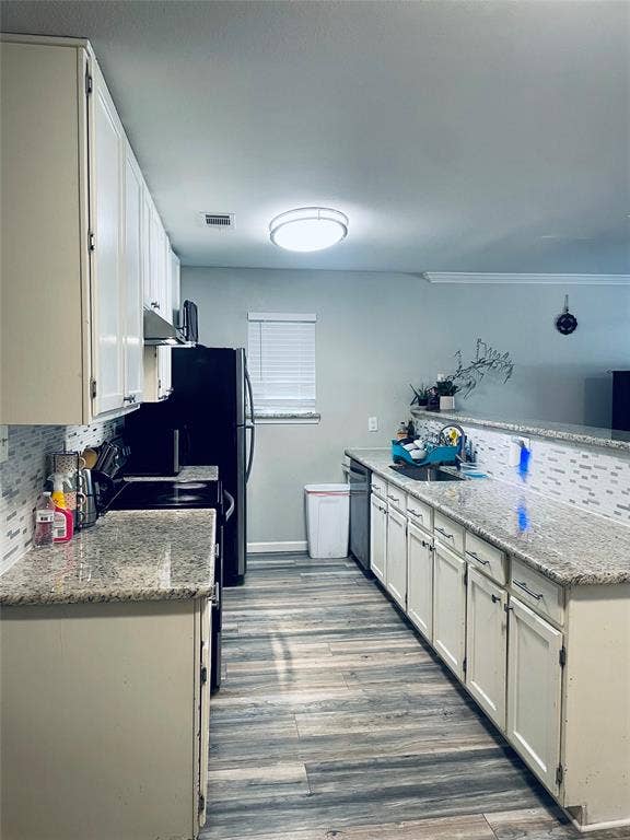 706 E High Street, Terrell, TX 75160 Kitchen featuring stone-finish countertops, white cabinetry, wood-finish flooring, and decorative tile backsplash