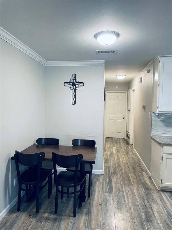 706 E High Street, Terrell, TX 75160 Wood-finish flooring throughout, white shaker-style cabinetry, stone-look countertops, glass tile backsplash, and crown molding