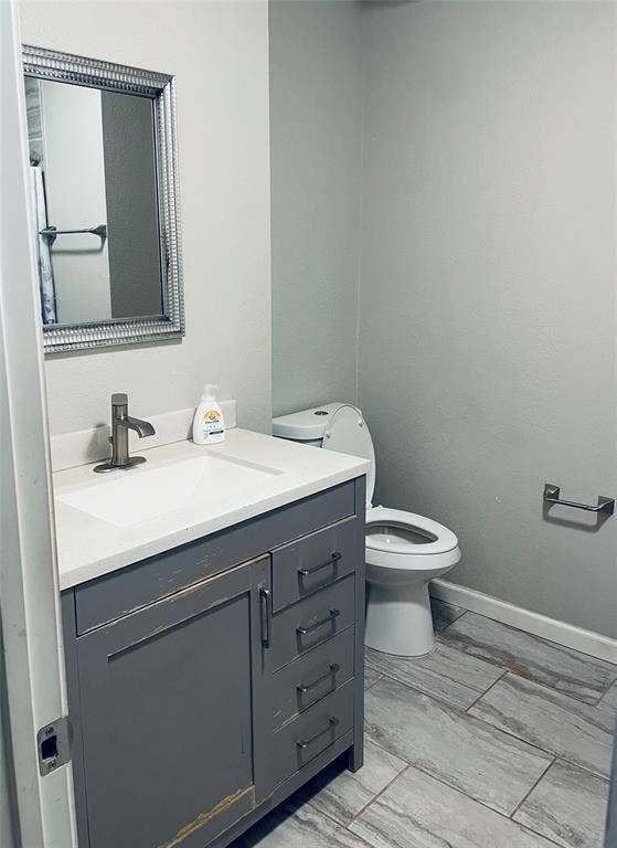 706 E High Street, Terrell, TX 75160 Gray vanity featuring a white solid-surface countertop with an integrated rectangular sink, single-handle brushed-finish faucet, and tile flooring