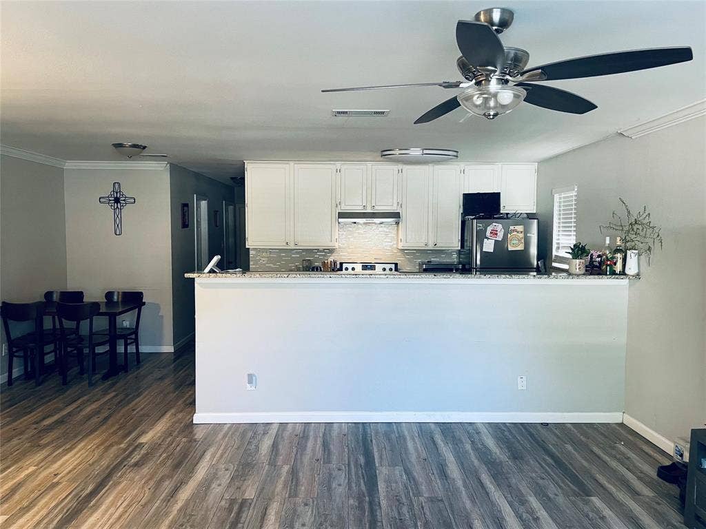 706 E High Street, Terrell, TX 75160 Kitchen featuring white cabinetry, stone-finish countertops, tile backsplash, wood-finish flooring, and a ceiling fan with integrated lighting