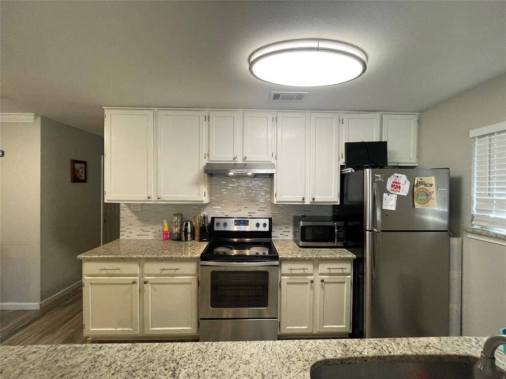 706 E High Street, Terrell, TX 75160 Kitchen featuring white cabinetry, stone-surface countertops, stainless steel appliances, and a tiled backsplash